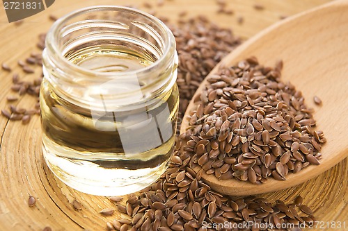 Image of Linseed oil and flax seeds on wooden background 