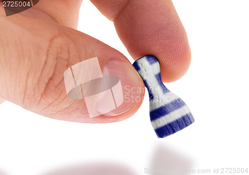 Image of Hand holding wooden pawn, flag painting, selective focus