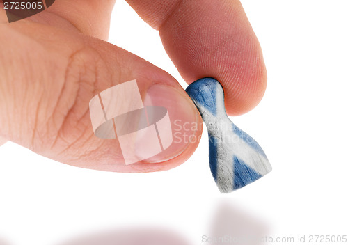 Image of Hand holding wooden pawn, flag painting, selective focus