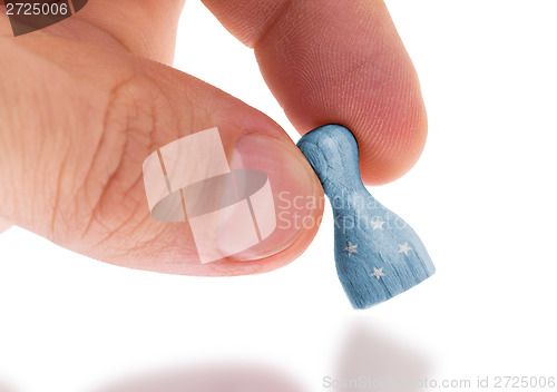 Image of Hand holding wooden pawn, flag painting, selective focus