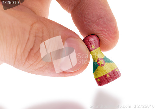 Image of Hand holding wooden pawn, flag painting, selective focus