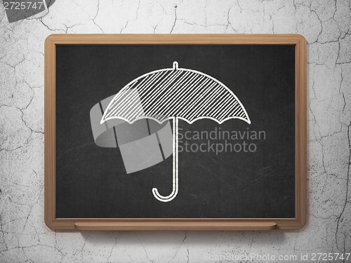 Image of Protection concept: Umbrella on chalkboard background