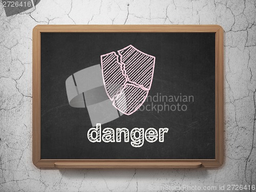 Image of Safety concept: Broken Shield and Danger on chalkboard background