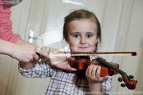 Image of cute preschool girl learning violin playing