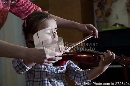 Image of adorable little girl learning violin playing