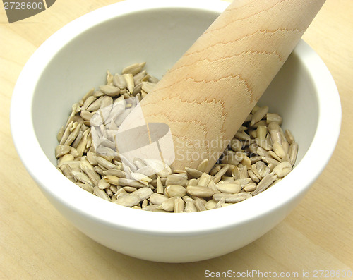 Image of Pestling sunflower seeds in a bowl of chinaware