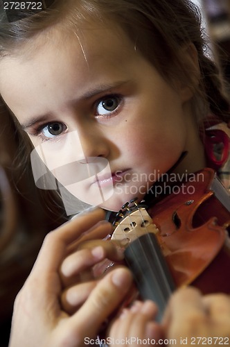 Image of adorable little girl learning violin playing