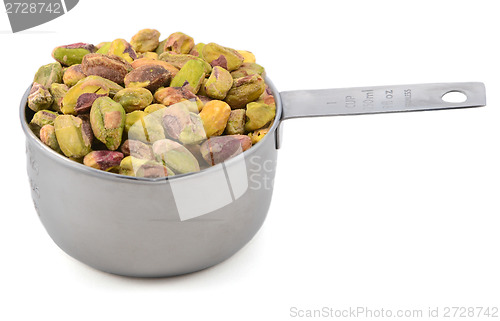 Image of Shelled pistachio nuts in a metal cup measure