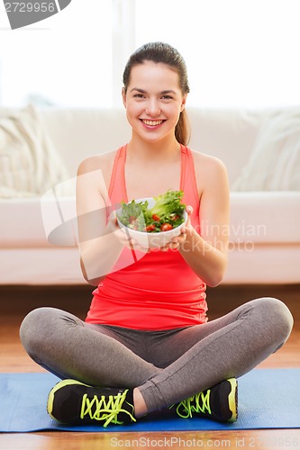 Image of smiling teenage girl with green salad at home