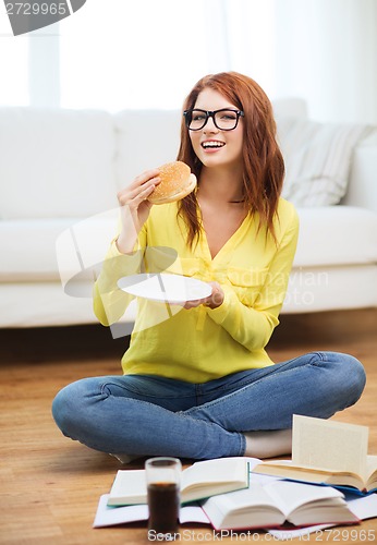 Image of student eating hamburger and doing homework