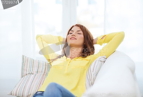 Image of smiling young woman lying on sofa at home