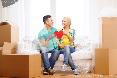 Image of smiling couple with red heart on sofa in new home