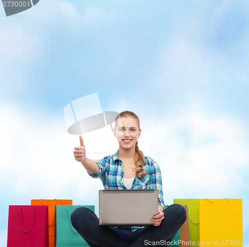 Image of smiling girl with laptop comuter and shopping bags