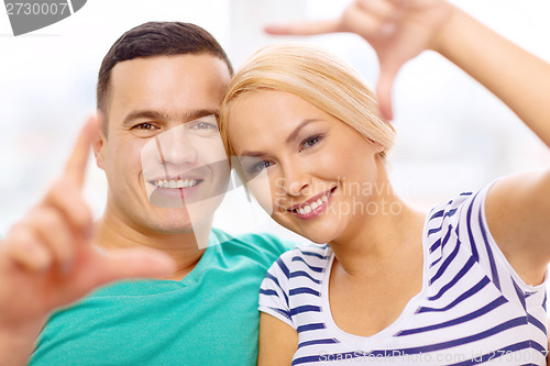 Image of smiling happy couple making frame gesture at home