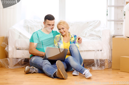 Image of couple with laptop sitting on floor in new house