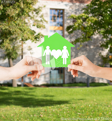 Image of hands holding green house with family