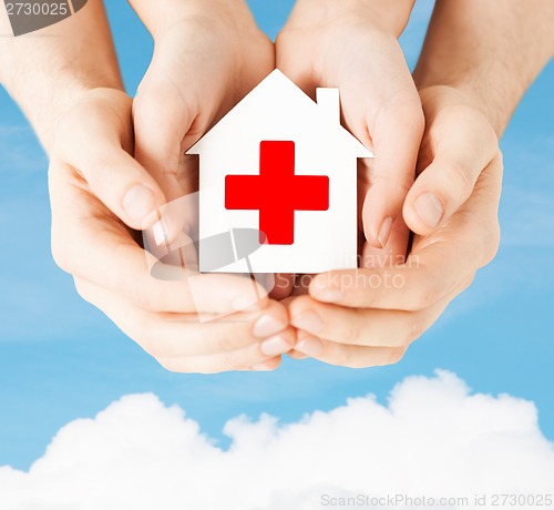 Image of hands holding paper house with red cross