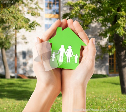 Image of hands holding green house with family