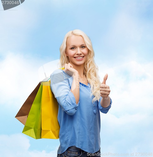 Image of smiling woman with shopping bags showing thumbs up