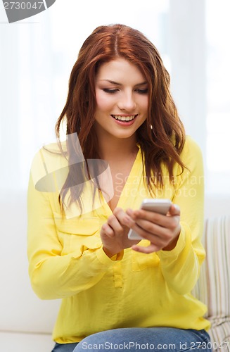 Image of smiling woman with smartphone at home