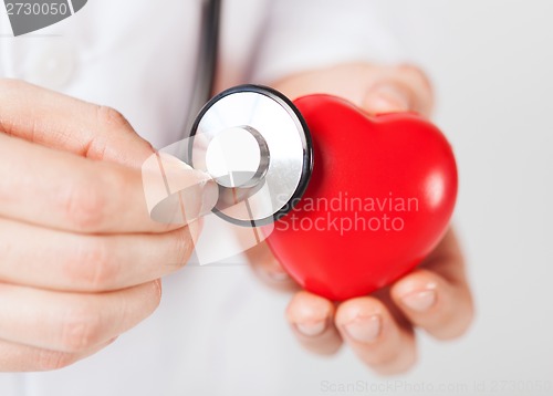 Image of male hands holding red heart and stethoscope