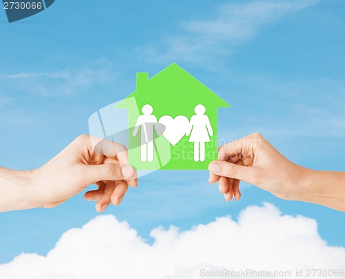 Image of hands holding green house with family