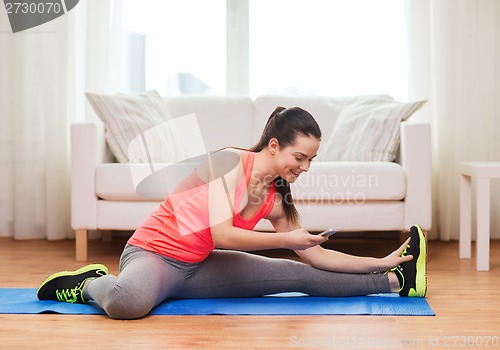 Image of smiling teenage girl streching on floor at home