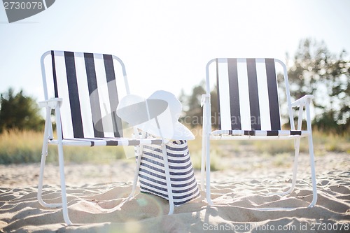 Image of two beach lounges with beach bag and white hat