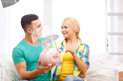 Image of smiling couple with piggybank in new home