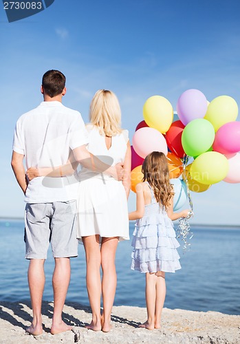 Image of happy family at the seaside with bunch of balloons