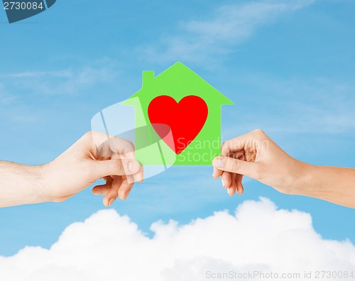 Image of couple hands holding green paper house