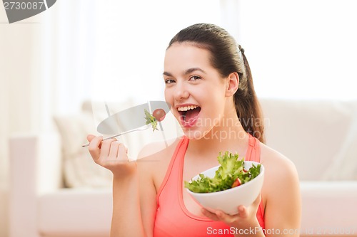 Image of smiling teenage girl with green salad at home