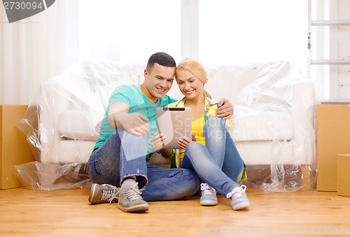 Image of smiling couple with tablet pc in new home