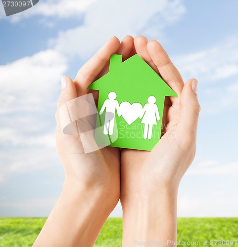 Image of hands holding green house with family