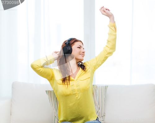 Image of teenage girl sitting on sofa with headphones