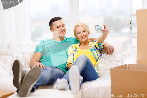 Image of smiling couple relaxing on sofa in new home