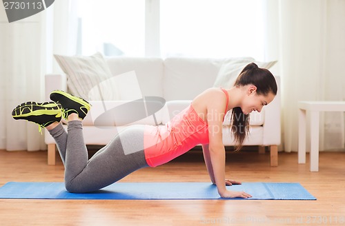 Image of smiling teenage girl doing push-ups at home