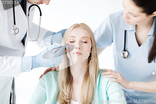 Image of plastic surgeon and nurse with patient