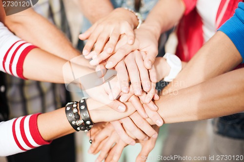 Image of teenagers hands on top of each other outdoors