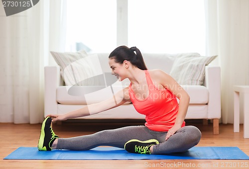 Image of smiling teenage girl streching on floor at home