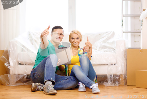 Image of smiling couple with tablet pc in new home