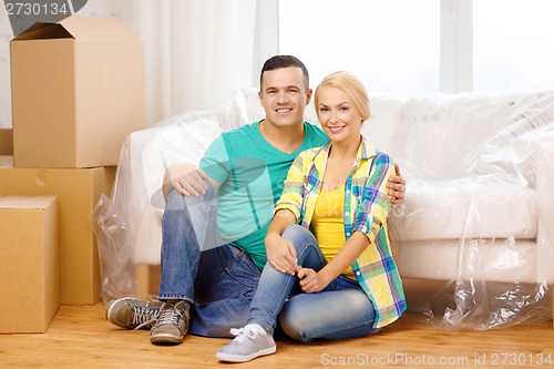 Image of smiling couple sitting on the floor in new house
