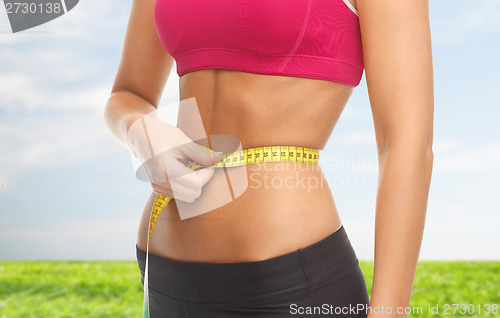 Image of close up of trained belly with measuring tape