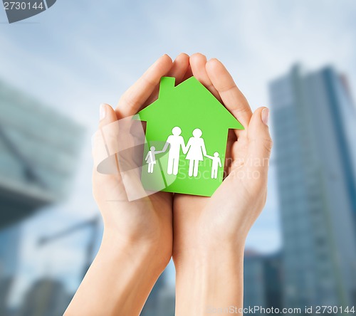 Image of hands holding green house with family