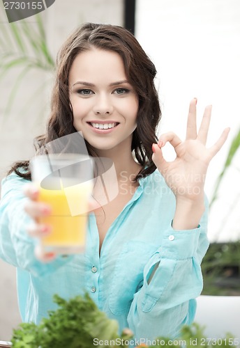 Image of woman with glass of orange juice showing ok sign