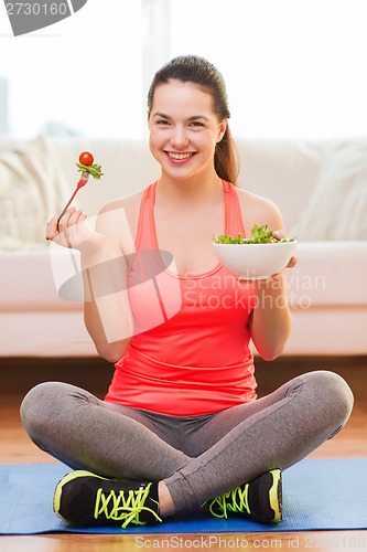 Image of smiling teenage girl with green salad at home