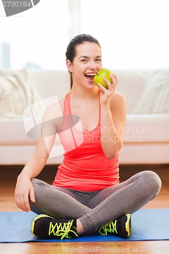 Image of smiling teenage girl with green apple at home