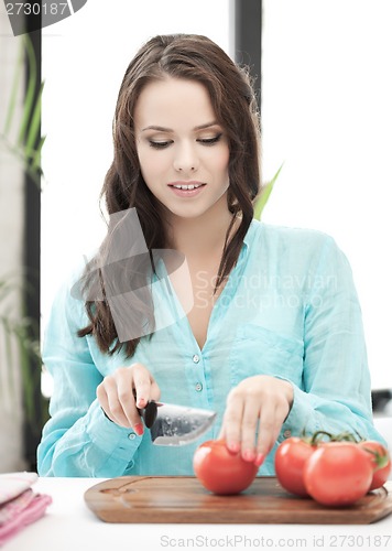 Image of beautiful woman in the kitchen cutting vegetables