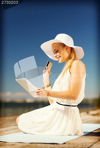 Image of woman in hat doing online shopping outdoors