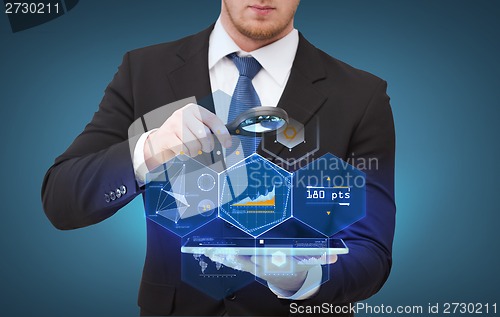Image of businessman hand holding magnifier over tablet pc